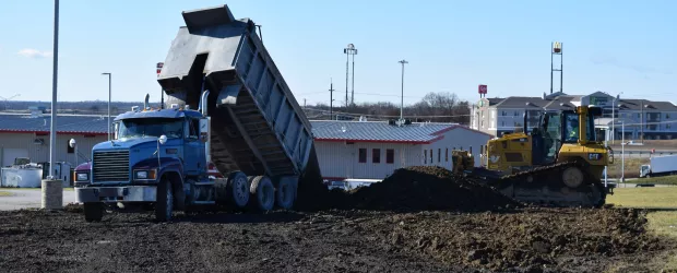 a dump truck is dumping dirt in front of a building