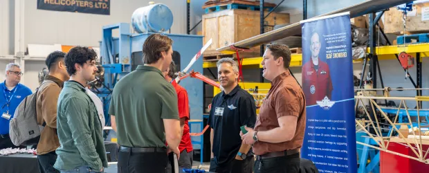 Students speak with aviation employers at Confederation College Aviation Day inside training hangar with aircraft equipment