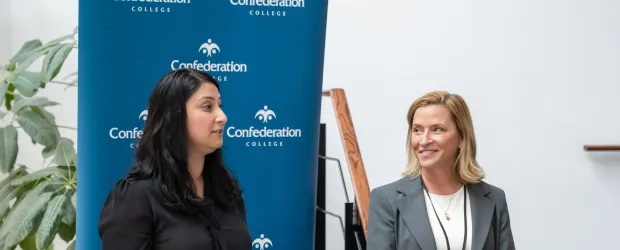 Two persons at podium during Confederation College announcement event with Alstom partnership backdrop.