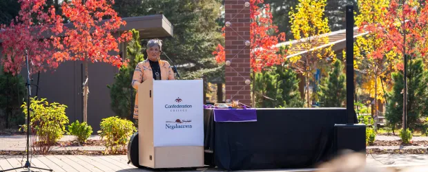 Speaker at Confederation College outdoor gathering during a campus Indigenous event in autumn