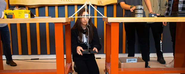 Students testing a model bridge with weights during a Confederation College engineering challenge