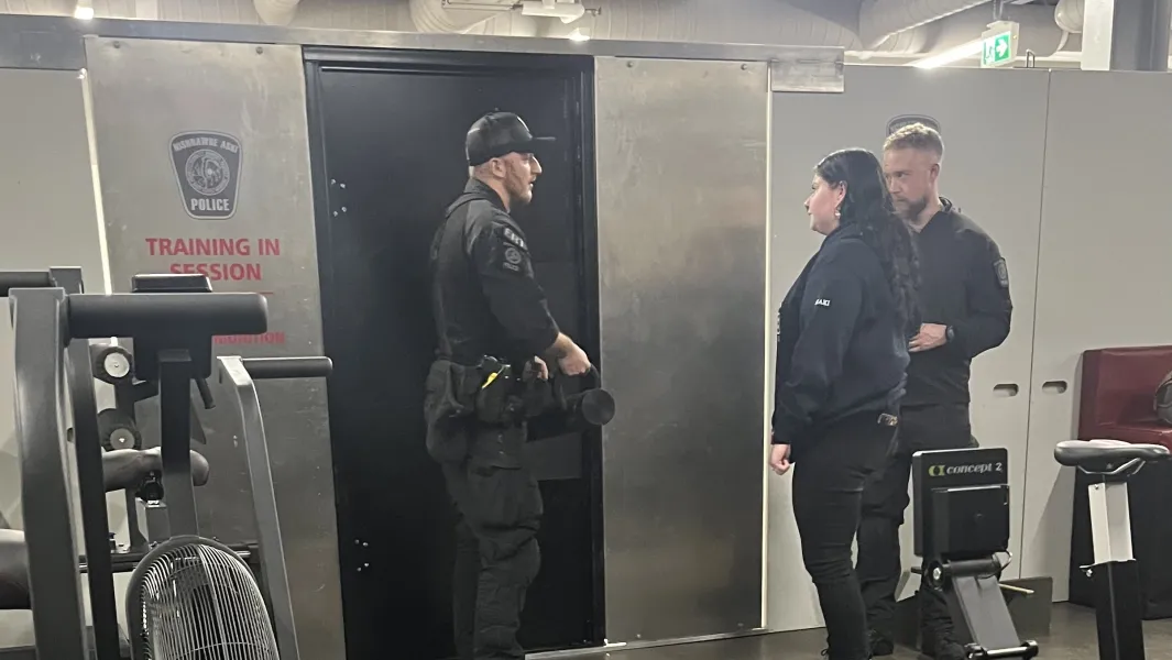 Police officers brief trainees during an indoor tactical training session