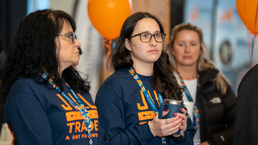 Attendees in “Jill of All Trades” shirts watching a presentation at a trades outreach event