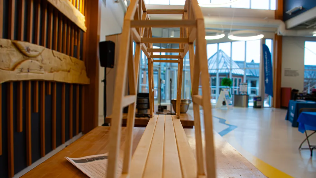 Wooden bridge model displayed for structural testing at a Confederation College engineering event