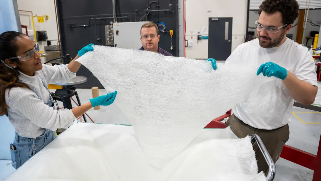 Students apply resin to fiberglass fabric during a hands-on composites manufacturing lab