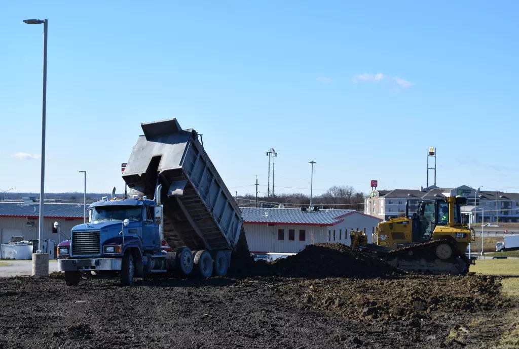a dump truck is dumping dirt in front of a building