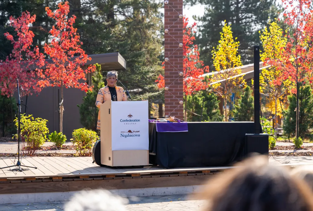 Speaker at Confederation College outdoor gathering during a campus Indigenous event in autumn