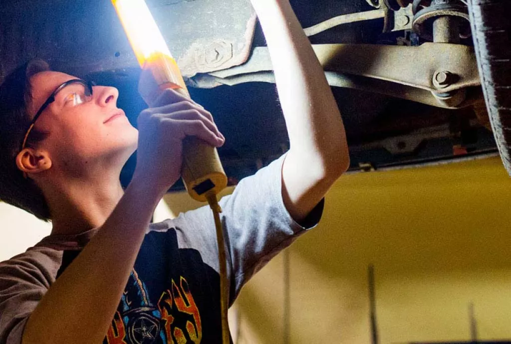 photo - Automotive student inspecting underside of a vehicle